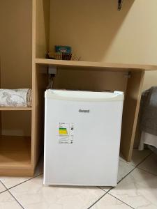a white refrigerator in a room with a shelf at Hotel Jovilá in Jaraguá do Sul