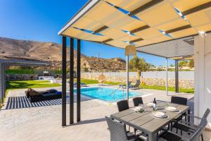 a patio with a table and chairs and a pool at Villa Livis 2 in Kiotari