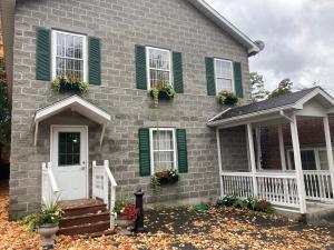 a gray brick house with green shutters and a porch at The Hotel Pratt in Cooperstown