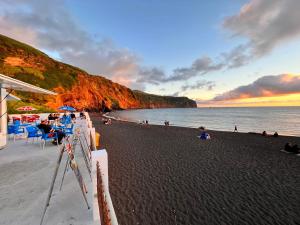 una spiaggia con un gruppo di persone sedute sulla spiaggia di WelcomeBuddy - Villa Mar Azul - Mosteiros Beach a Mosteiros