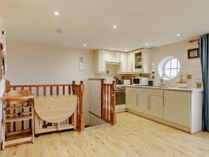 a kitchen with white cabinets and a wooden floor at 1 Bed in Sidmouth HAYES in Newton Poppleford