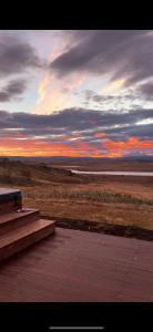a bench sitting on a deck with a sunset at Luxury villa with hot tub & amazing view in Reykholt