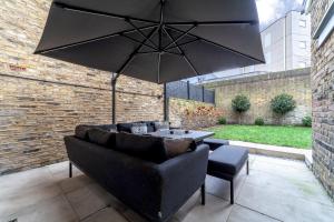 a patio with a couch and a table and an umbrella at The New Cross Premier Rooms in London