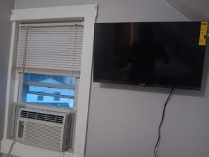 uma televisão de ecrã plano pendurada numa parede ao lado de uma janela em The Attic Room # 1 at The North End. NEW PRIVATE ROOM near Providence College em Providence