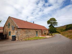 a stone building with a red roof next to a road at 2 bed in Osmotherley G0108 in Chop Gate
