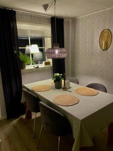 a dining room table with chairs and a purple lamp at Litet hus på landet 