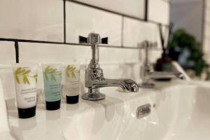 a bathroom sink with three bottles of soap and a faucet at Cosy Cottage By MGroupSA in Aberdare