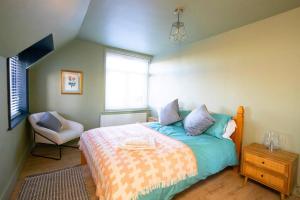 1 dormitorio con 1 cama y 1 silla en Main house + Annex, en Farningham