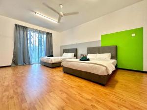 a bedroom with two beds and a green wall at Ipoh IGB Homestay by Comfort Home in Ipoh