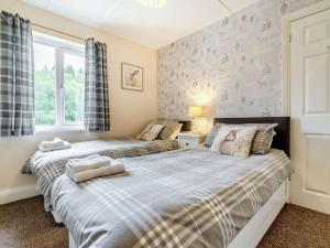 two beds in a bedroom with two windows at 2 Bed in Kielder 89299 in Falstone