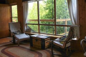 a living room with two chairs and a large window at Blue Vista Tobermory Waterfront Cottage in Tobermory