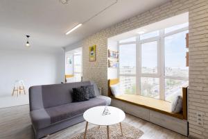 a living room with a couch and a large window at Loft Apartment in Ivano-Frankivsʼk