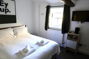 a bedroom with a white bed with towels on it at Redmire Village Pub in Redmire