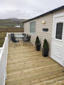 a deck with chairs and a table on a house at M&C Caravan Hire Sunnysands in Barmouth