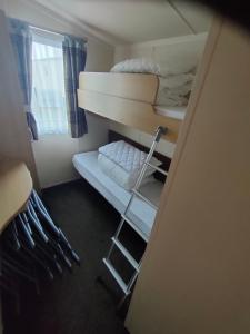a small room with a bunk bed and a ladder at M&C Caravan Hire Sunnysands in Barmouth