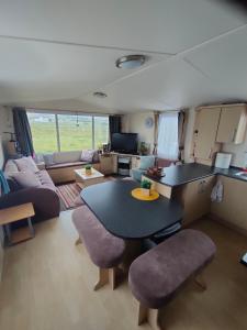 a kitchen and living room with a table and chairs at M&C Caravan Hire Sunnysands in Barmouth