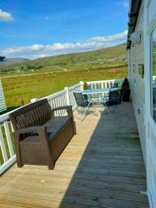 a wooden deck with a table and chairs on a house at M&C Caravan Hire Sunnysands in Barmouth