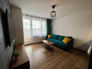 ein Wohnzimmer mit einem grünen Sofa und einem Tisch in der Unterkunft Moderný apartmán s krásnym výhľadom v top lokalite in Žilina