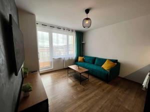 a living room with a green couch and a table at Moderný apartmán s krásnym výhľadom v top lokalite in Žilina