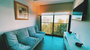 a living room with a blue couch and a large window at Apartamento zona 13 Aeropuerto Inara in Guatemala