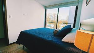 a bedroom with a blue bed with a large window at Apartamento zona 13 Aeropuerto Inara in Guatemala