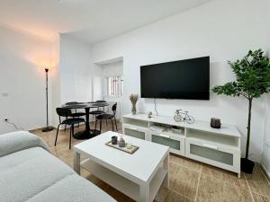a white living room with a tv and a table at Oasis Suite in Avila