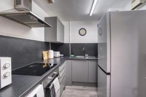 una cocina con armarios blancos y un reloj en la pared en #71 Phoenix Court By DerBnB, Industrial Chic 1 Bedroom Apartment, Wi-Fi, Netflix & Within Walking Distance Of The City Centre en Sheffield
