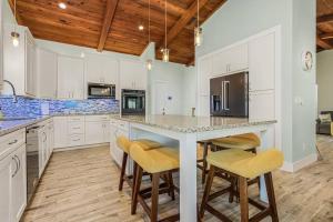 uma cozinha com armários brancos e uma grande ilha com bancos de bar em Anchors Away - Pool with Spa - Garage Game Room em Cape Coral