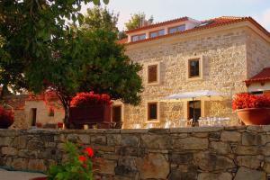 a stone building with an umbrella and a stone wall at Otium Country House in Alvorge