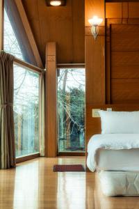 a bedroom with a bed and a large window at Pine Tree Resort  in Zhushan