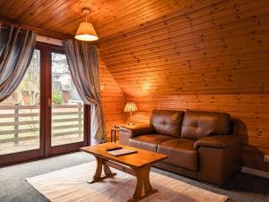 a living room with a leather couch and a table at Macha 3 - Hot Tub-Perth-Pets-Family-Luxury-Cabin in Perth