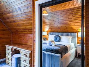 ein Schlafzimmer mit einem Bett in einer Holzwand in der Unterkunft Macha 3 - Hot Tub-Perth-Pets-Family-Luxury-Cabin in Perth