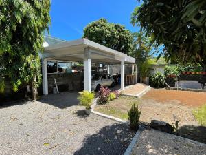 a white pavilion with a car parked under it at Kowlessur Residence in Surinam