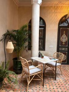 eine Terrasse mit einem Tisch, Stühlen und Pflanzen in der Unterkunft Riad Bamaga in Marrakesch