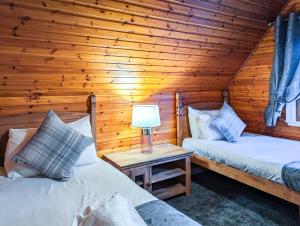 2 Betten in einem Blockhaus mit einer Lampe auf einem Tisch in der Unterkunft Macha 3 - Hot Tub-Perth-Pets-Family-Luxury-Cabin in Perth