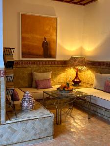 uma sala de estar com um sofá e uma pintura na parede em Riad Bamaga em Marraquexe