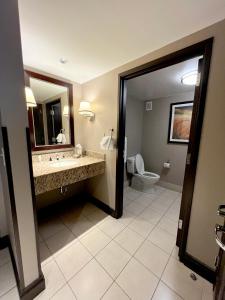 ein Badezimmer mit einem Waschbecken, einem WC und einem Spiegel in der Unterkunft Ameristar Casino Hotel Vicksburg, Ms. in Vicksburg