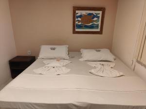a bed with white sheets and towels on it at Pousada Bellas Artes in Mata de Sao Joao