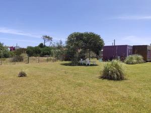 un champ d'herbe avec un bâtiment et des arbres dans l'établissement Casa en La Paloma cerca de la playa, à La Paloma