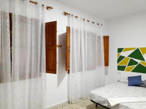 1 dormitorio con paredes blancas, 1 cama y ventana en CASA DE PUEBLO Fuente Buena en Arroyo del Ojanco