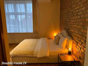 a bedroom with a bed and a brick wall at Metropolitan Rooms in Belgrade