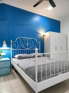 a blue bedroom with a white bed and a blue wall at DH Merlimau Homestay in Merlimau