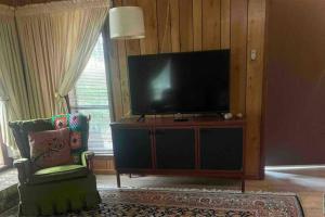 a living room with a flat screen tv and a chair at Large 3 Bedroom 70's Home - Benton, AR in Benton