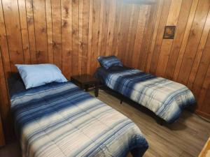 Large 3 Bedroom 70's Home - Benton, AR في بينتون: سريرين في غرفة بجدران خشبية