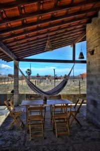 eine Hängematte auf einer Terrasse mit Tischen und Stühlen in der Unterkunft Alto das Carnaúbas Chalé in Luis Correia