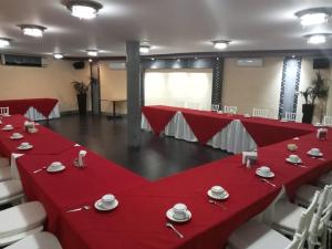 une salle de conférence avec des tables et des chaises rouges et un écran dans l'établissement HOTEL VILLA LAS ROSAS TEPIC, à Tepic