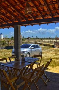 einen Tisch und Stühle auf einer Terrasse mit einem Auto in der Unterkunft Alto das Carnaúbas Chalé in Luis Correia