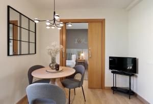 comedor con mesa, sillas y TV en Apartments Barcelona & Home Deco Eixample, en Barcelona