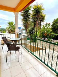 een balkon met een tafel en stoelen en palmbomen bij La villa du Paradis du Coto - Piscine-Mer&Surf in Coto