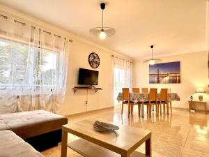 een woonkamer met een bank en een tafel en stoelen bij La villa du Paradis du Coto - Piscine-Mer&Surf in Coto